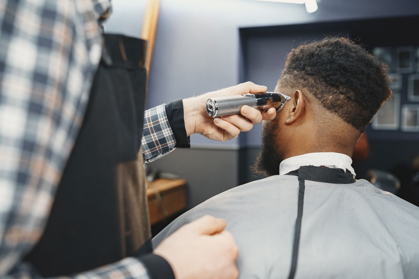 A barber running clippers along a man's fade