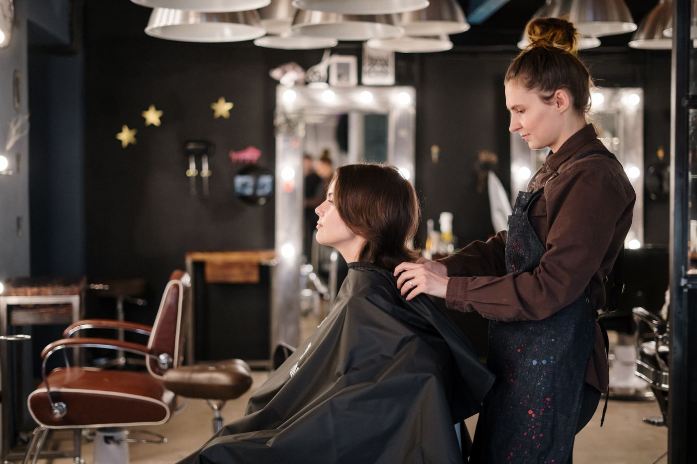 A stylist settling a cape on a client's shoulders before a cut
